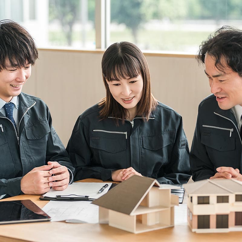 高品質な建築設計と住宅建築の提案を行う株式会社エフ・アール・シーの社員が模型を見ながら打ち合わせしている写真です。.